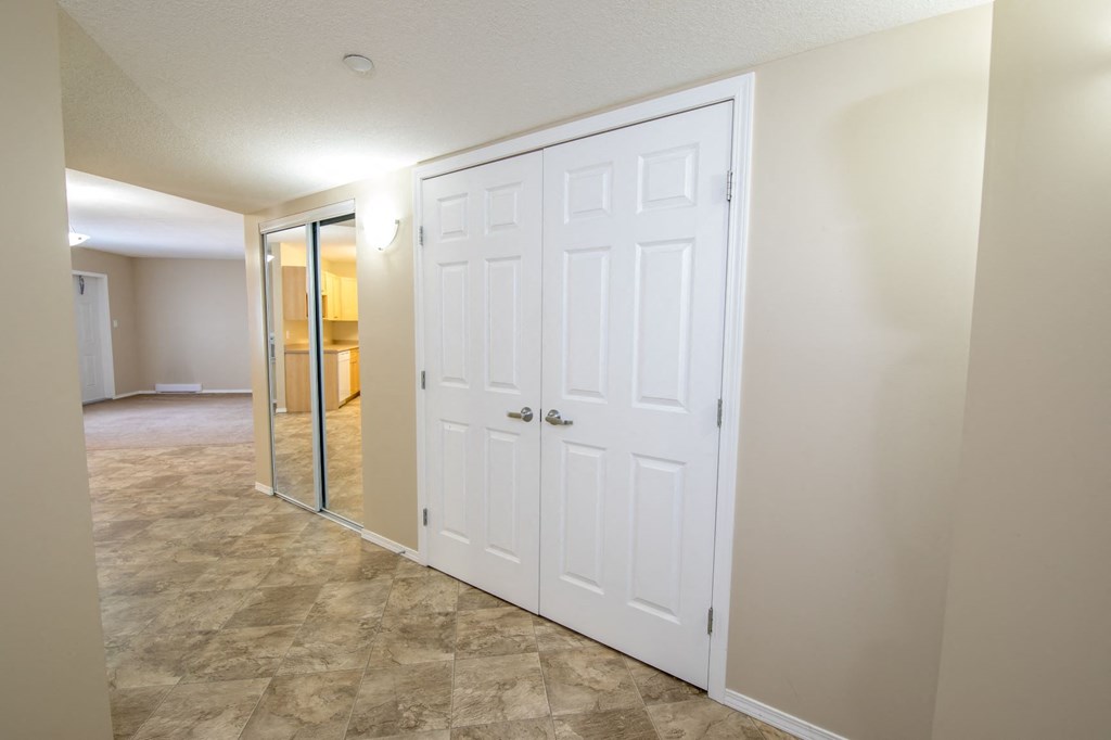 an empty room with a white door and a mirrored closet