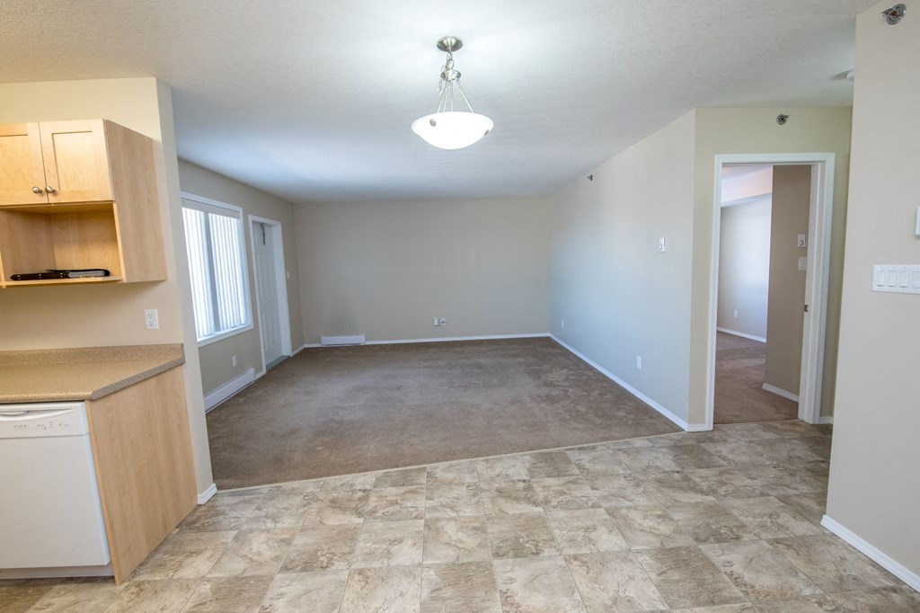 an empty living room with a kitchen and an empty dining room