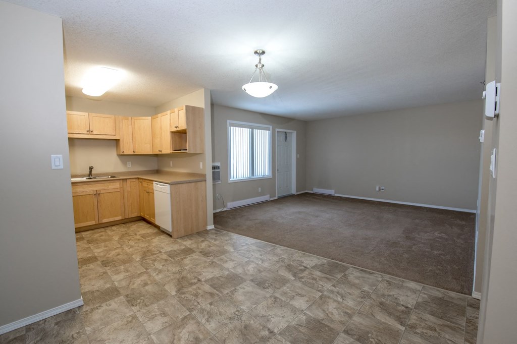 an empty living room and kitchen with wood cabinets