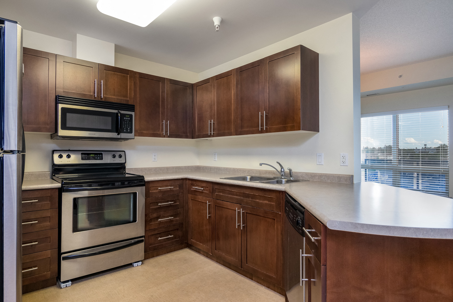 an empty kitchen with wooden cabinets and stainless steel appliances