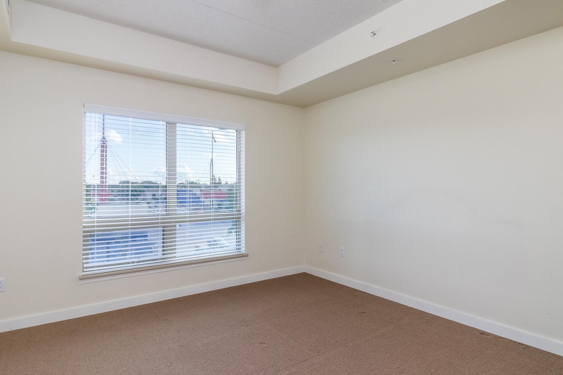 the living room of an apartment with a large window and white walls