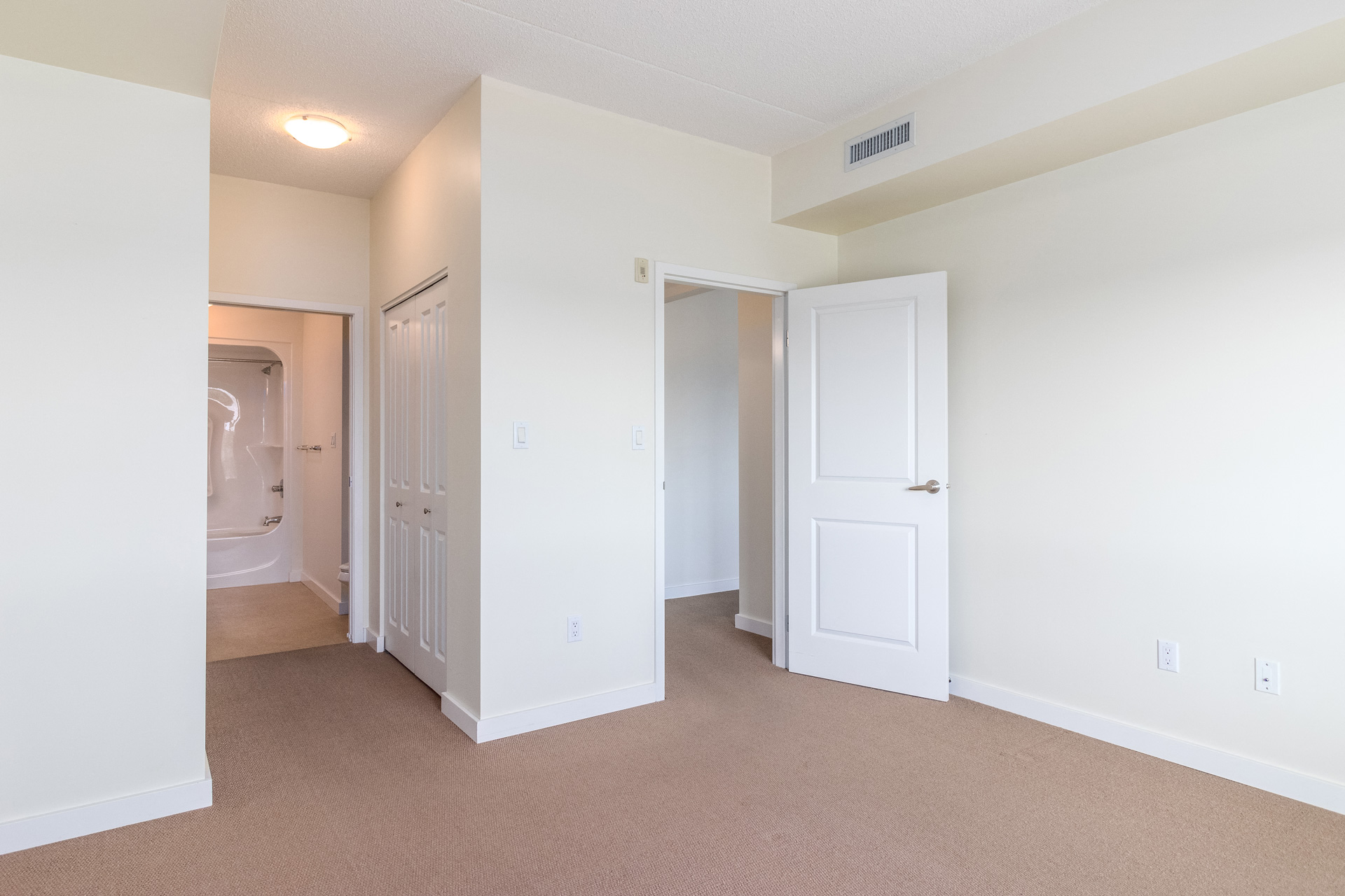 a bedroom with white walls and a closet and a bathroom