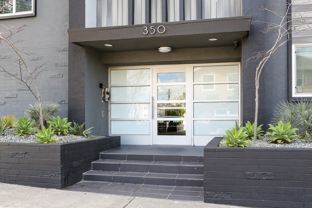 the front door of a house with steps and plants in front of it