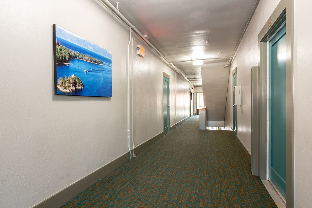 a long corridor with a painting on the wall and doors on the side