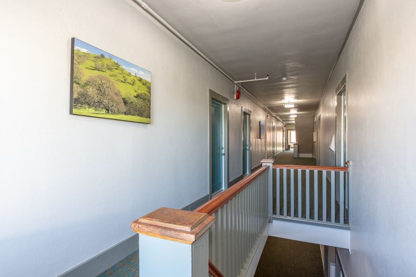 a hallway of a building with a painting on the wall and a staircase