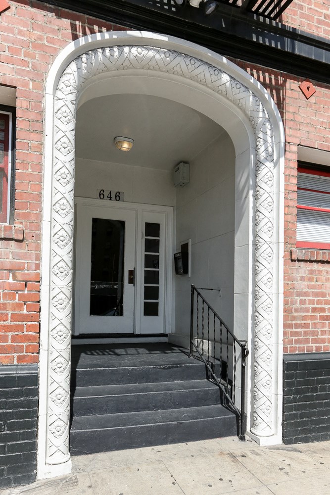 the front door of a brick building with a white archway and stairs
