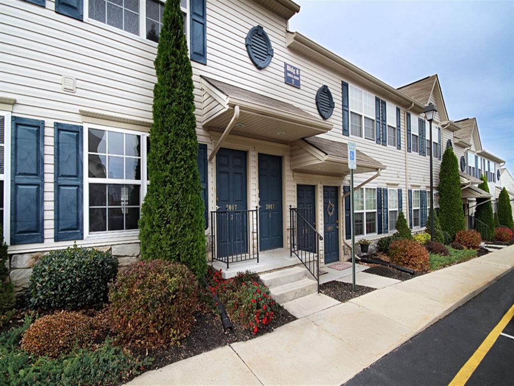 the front of a building with blue doors and a sidewalk