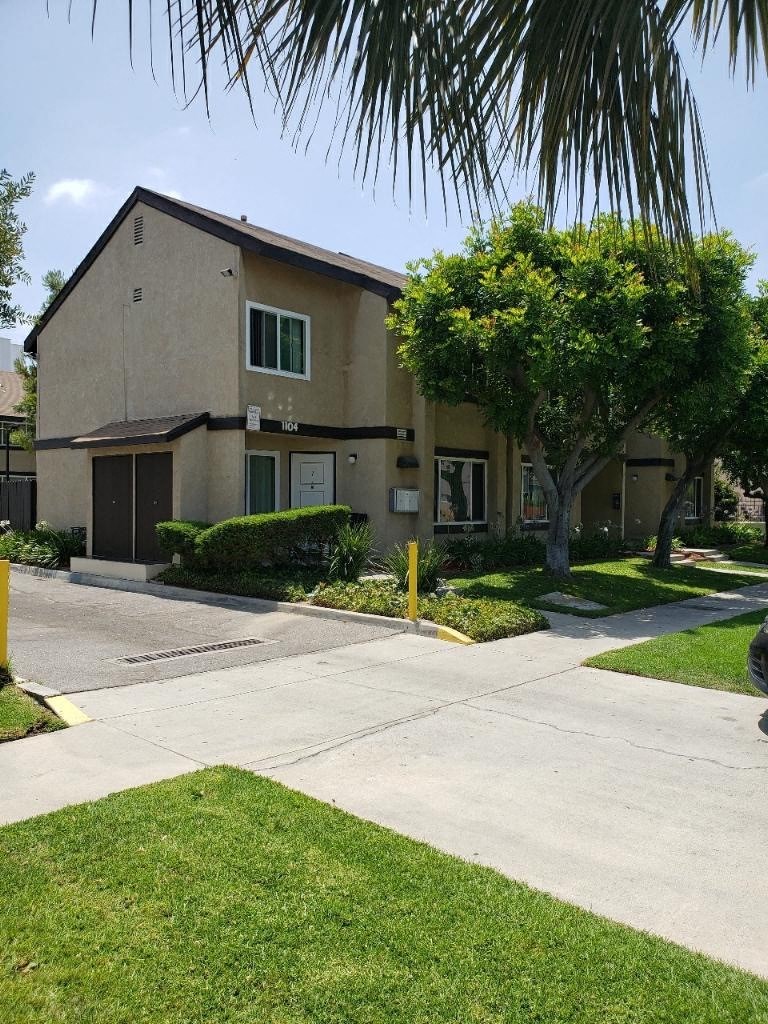 a house with a sidewalk and a tree in front of it