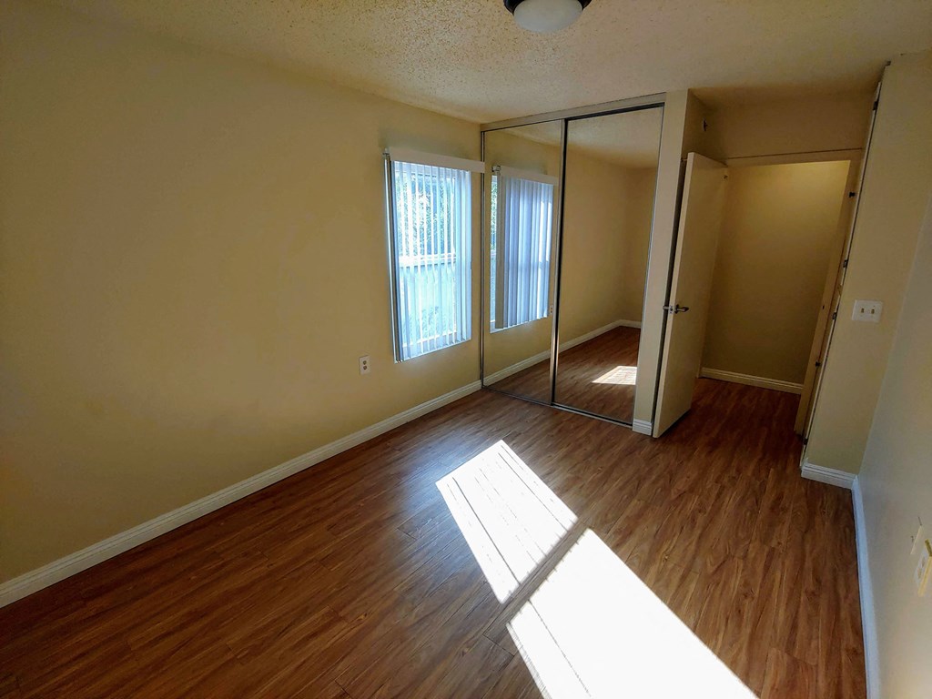 an empty living room with wood floors and a mirror