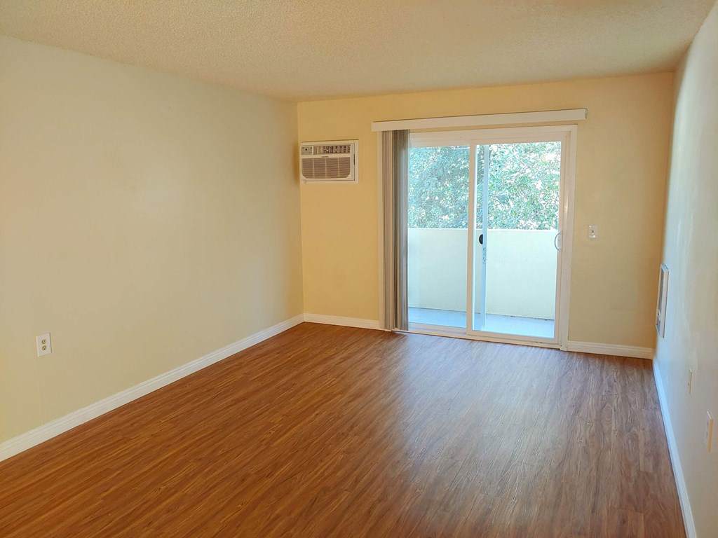 an empty living room with wood floors and a sliding glass door