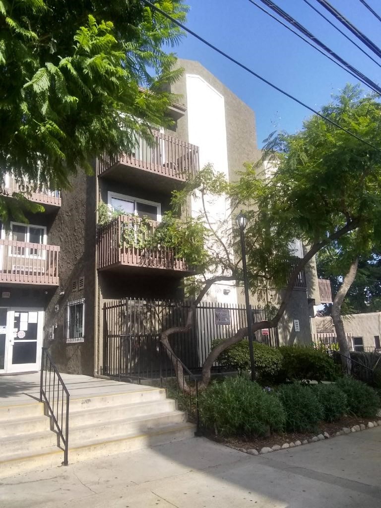 an apartment building with stairs and trees in front of it