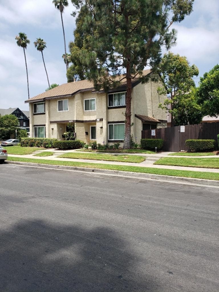 a house on the corner of a street with palm trees