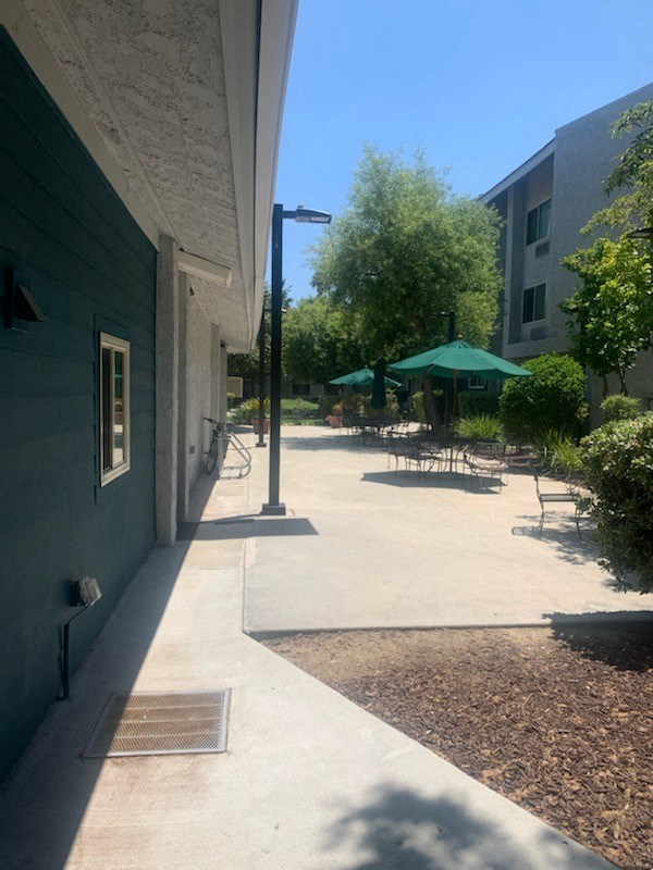 a sidewalk in front of a building with tables and umbrellas