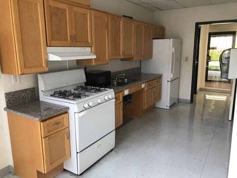an empty kitchen with white appliances and wooden cabinets