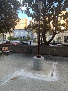 a street light on the sidewalk next to some benches