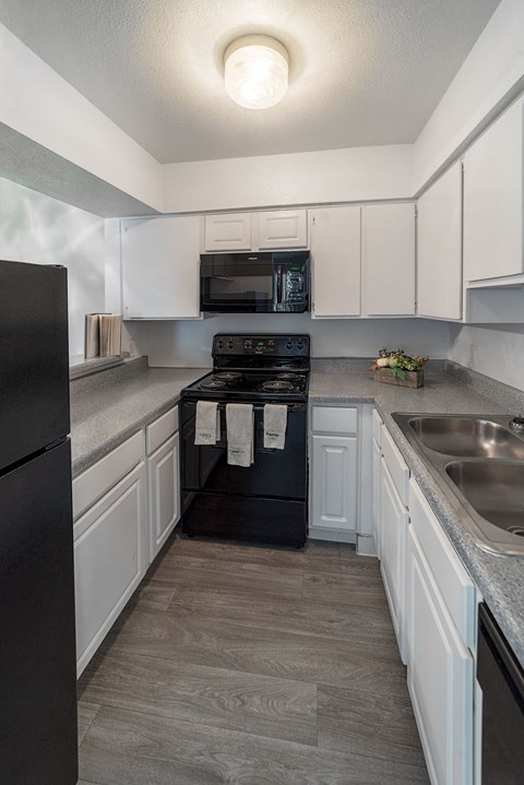 a kitchen with white cabinets and black appliances