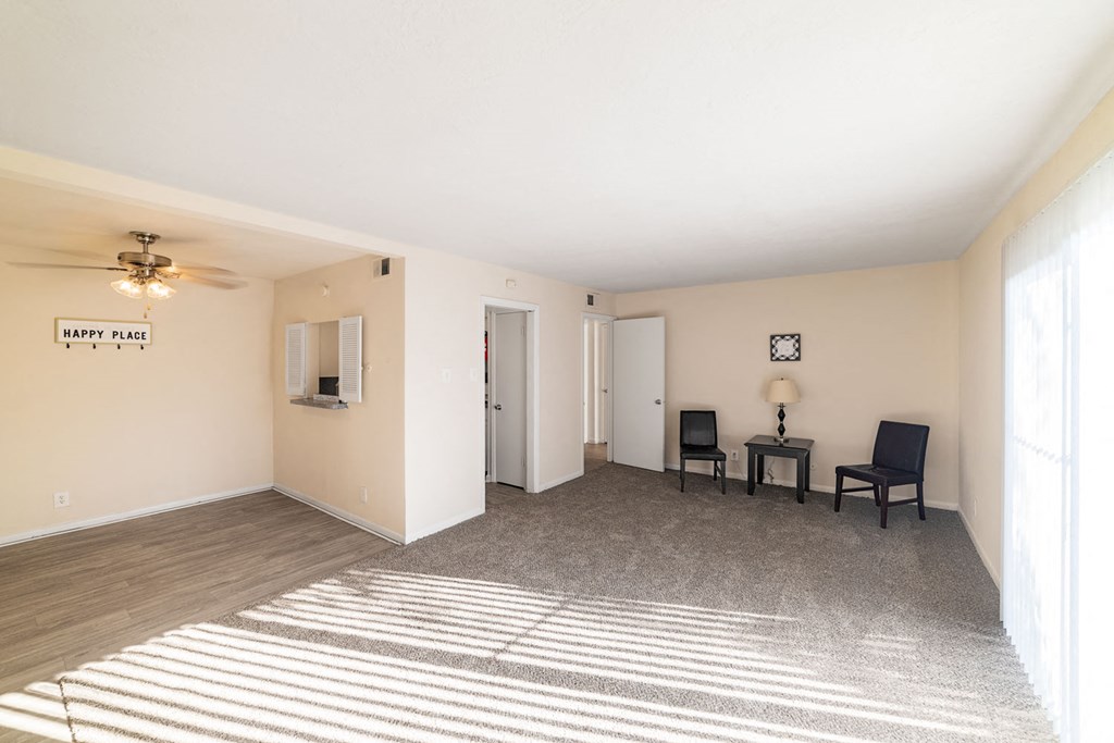 a living room with a rug and chairs and a window