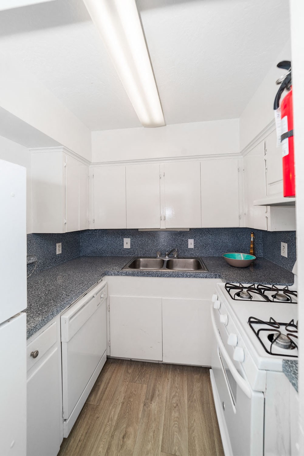 a white kitchen with white appliances and gray counter tops