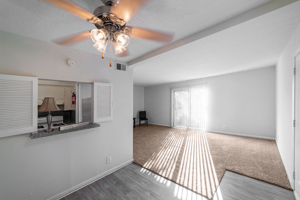 an empty living room with a ceiling fan