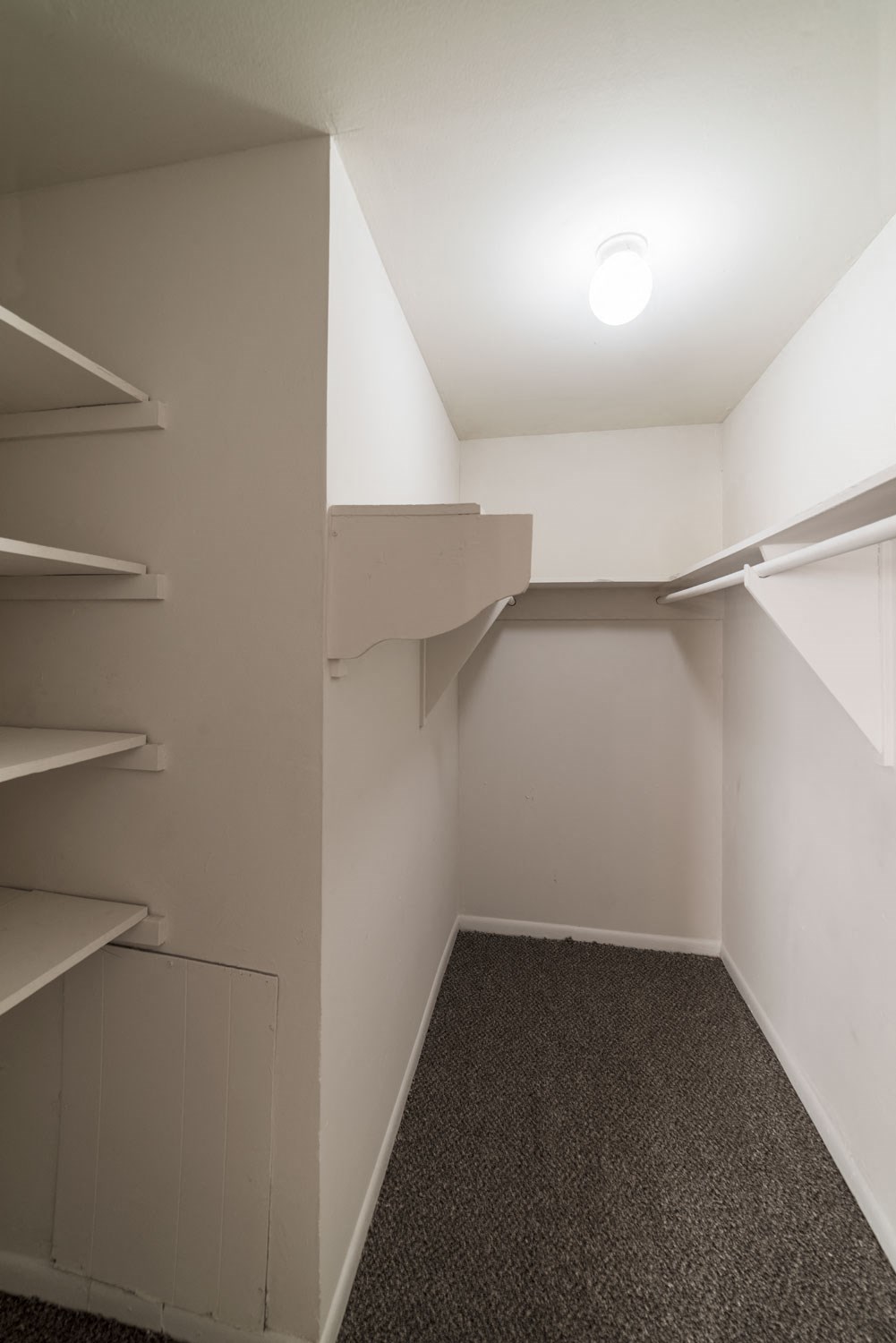 a walk in closet in a small room with shelves