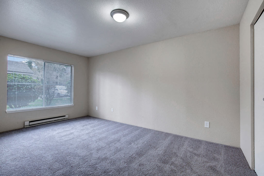 an empty living room with a large window and carpet