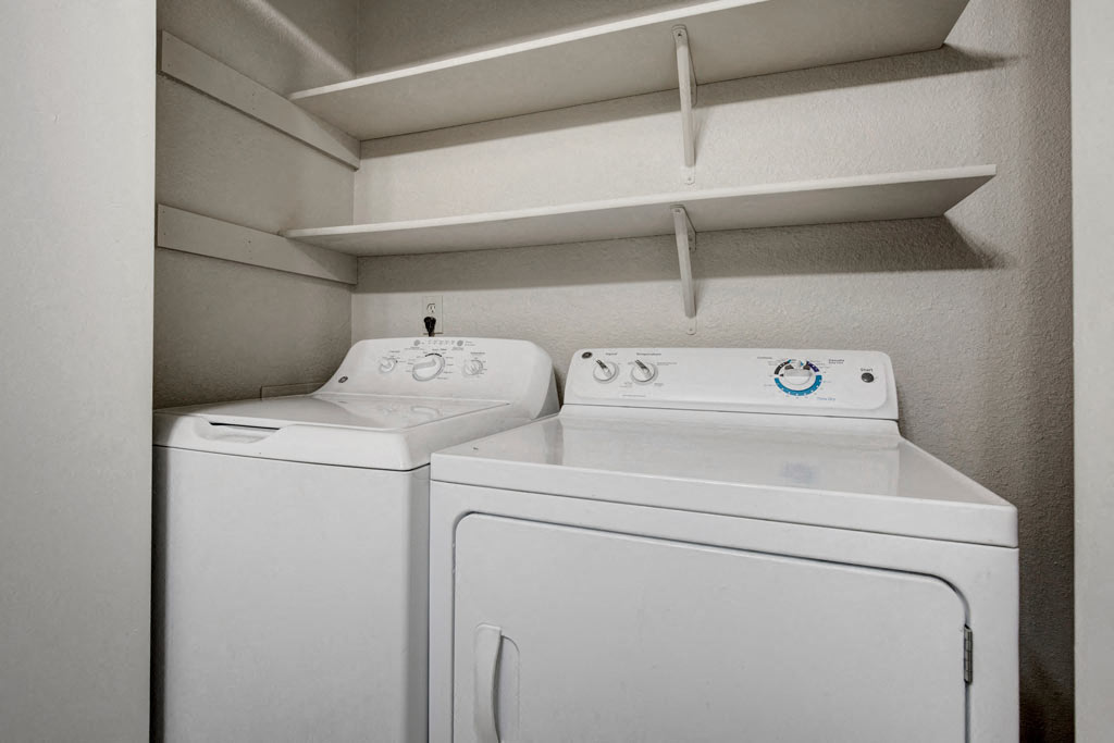 a white laundry room with two washes and a dryer