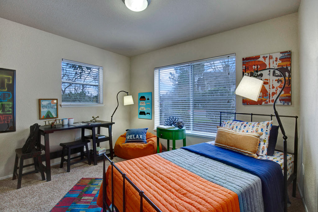 a bedroom with a bed and a desk and a window