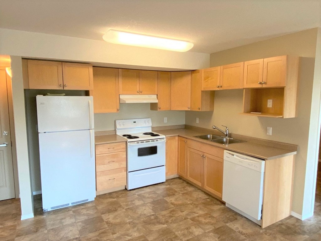 an empty kitchen with white appliances and wooden cabinets