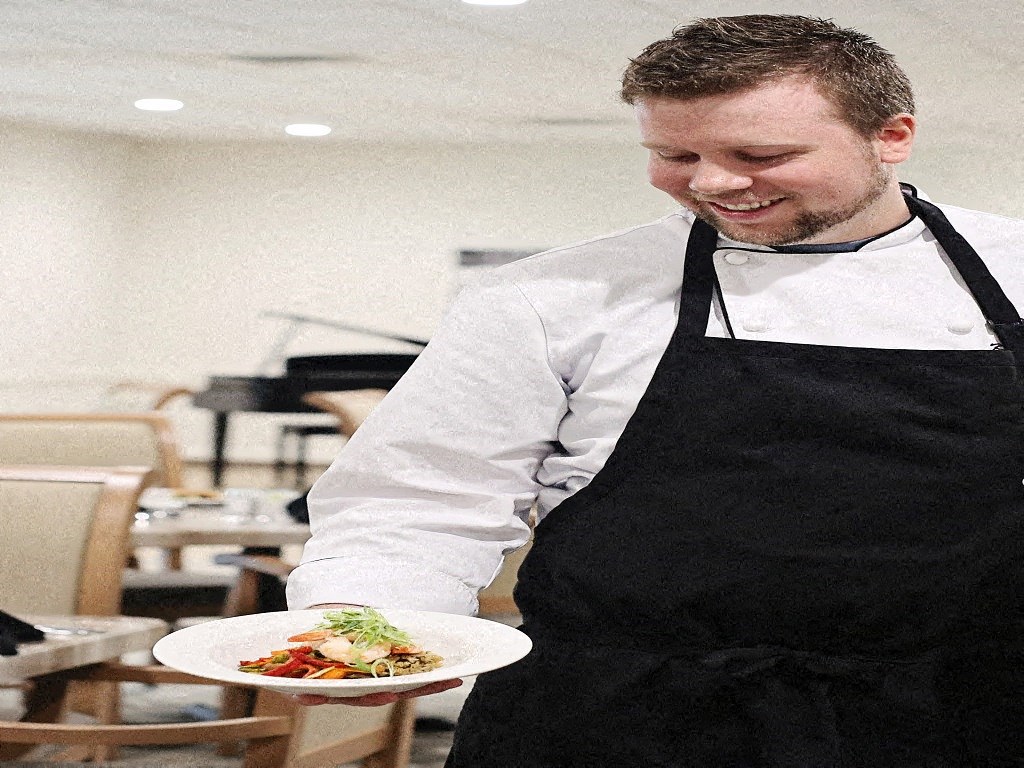 a man in an apron holding a plate of food