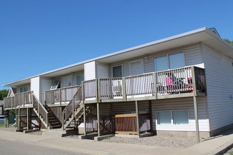 the exterior of an apartment building with stairs and a balcony