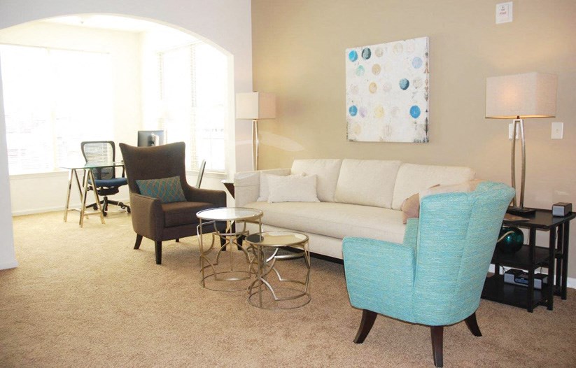 a living room with a white couch and two blue chairs