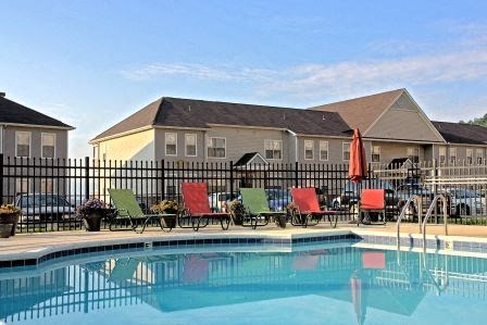 a swimming pool with chairs in front of a building