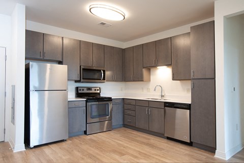 A kitchen with a refrigerator, microwave, oven, and sink.