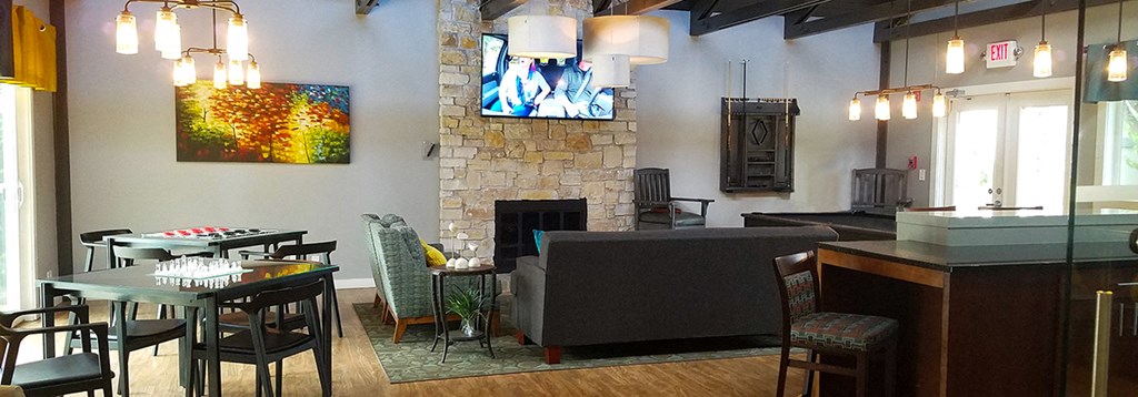 a living room with a stone fireplace and tables and chairs