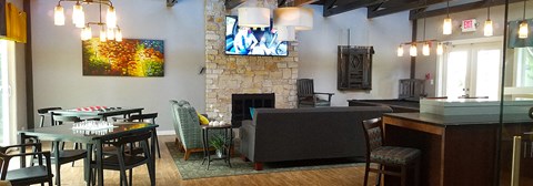 a living room with a stone fireplace and tables and chairs