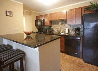 a kitchen with a granite counter top and a black refrigerator