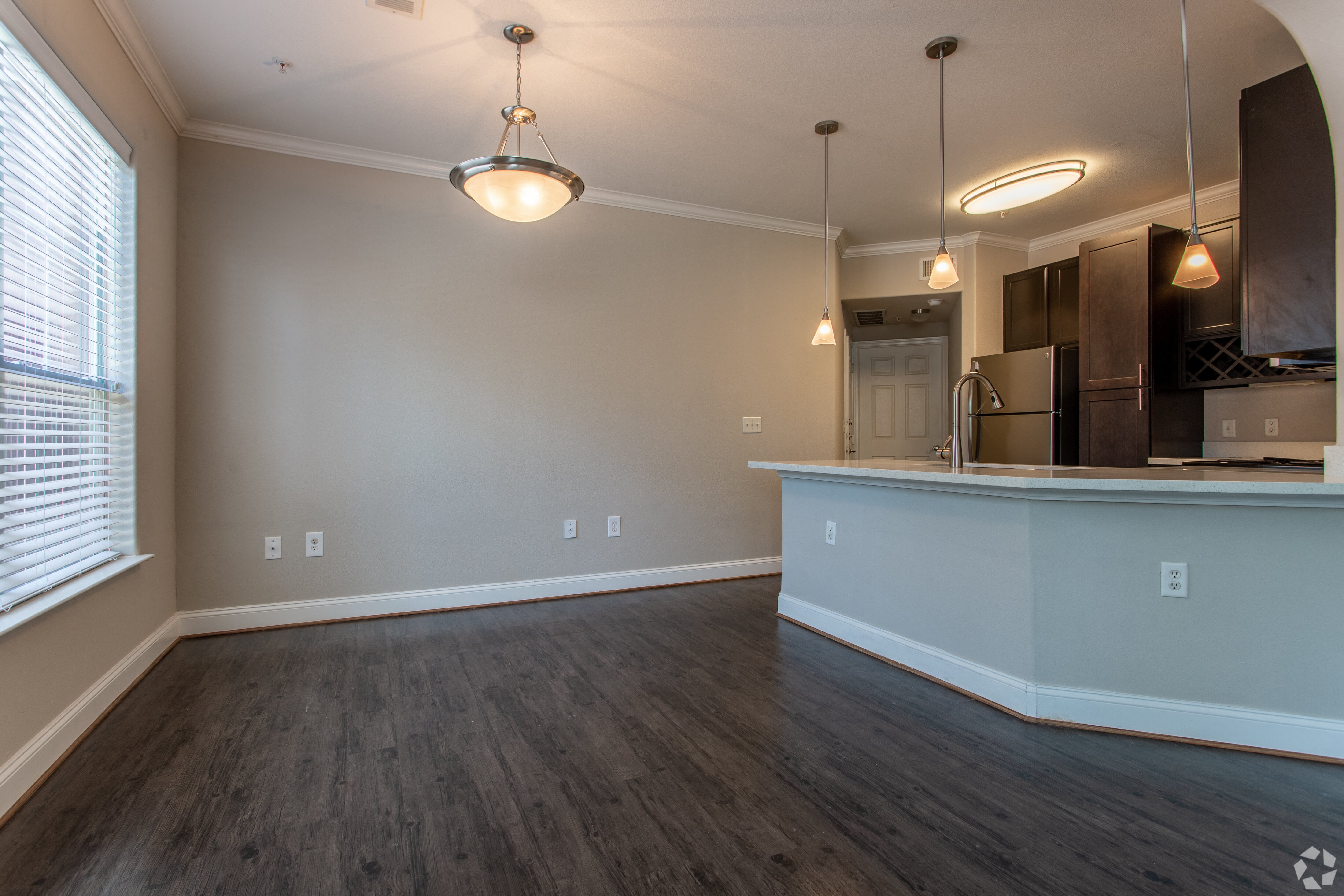 an empty living room with a kitchen and a large window