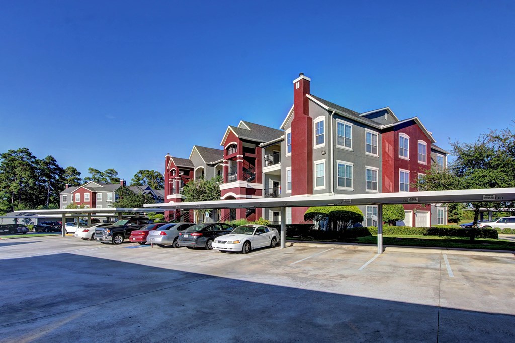 a parking lot with cars in front of a row of apartment buildings