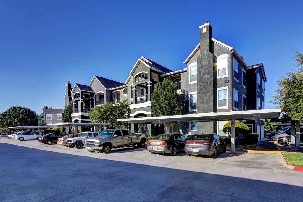 a parking lot with cars in front of an apartment building
