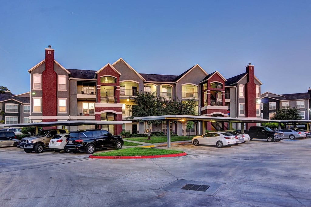 a parking lot with cars in front of an apartment building