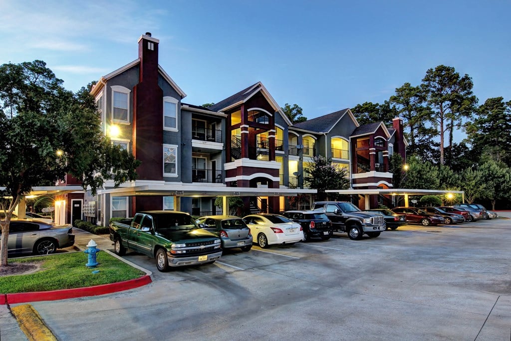 a row of apartment buildings with cars parked in front