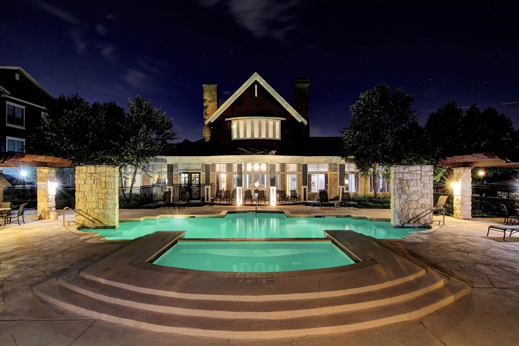 a swimming pool at night with a house in the background