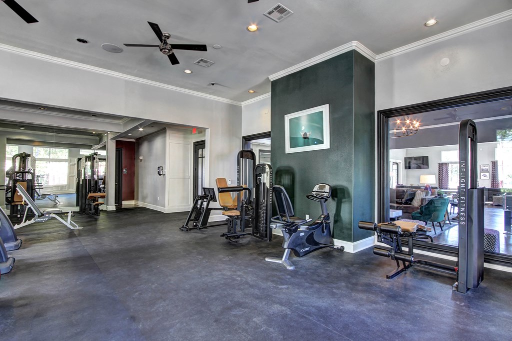 a workout room with various exercise equipment and a ceiling fan