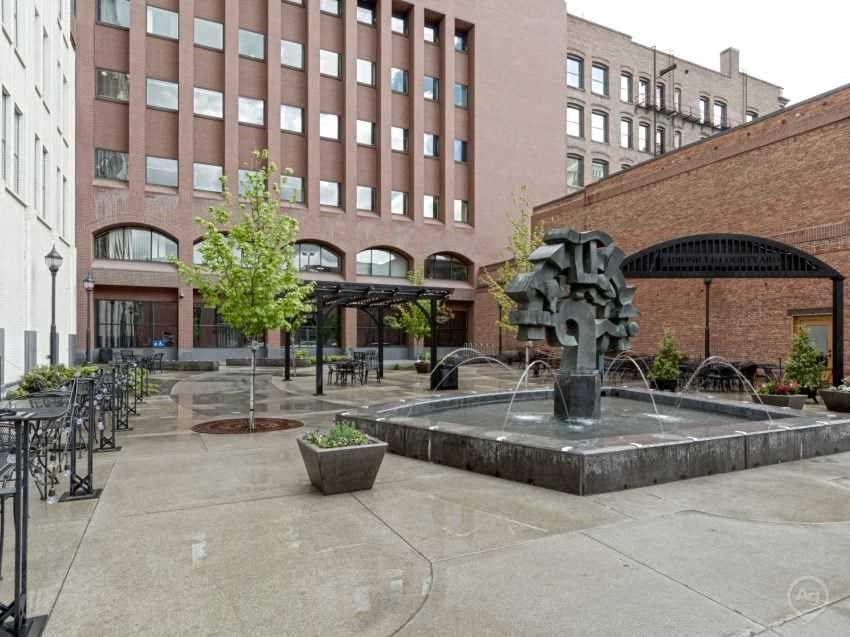 a courtyard with a fountain in front of a tall building