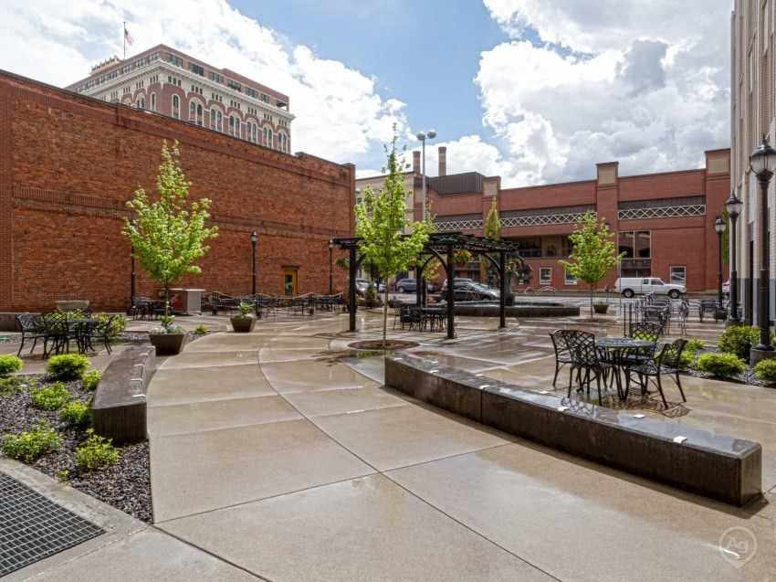 a courtyard with tables and chairs in front of a brick building