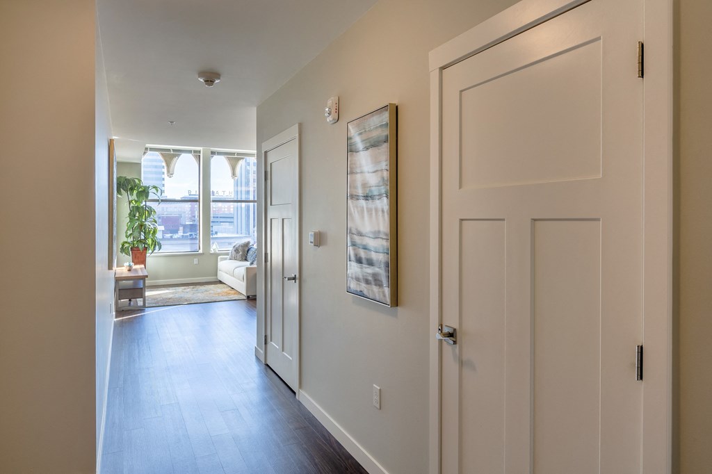 a hallway with a white door and a living room with a window