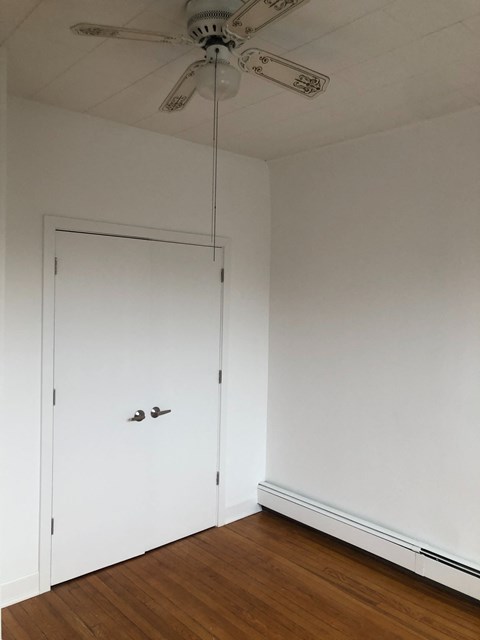 a bedroom with a white door and a ceiling fan