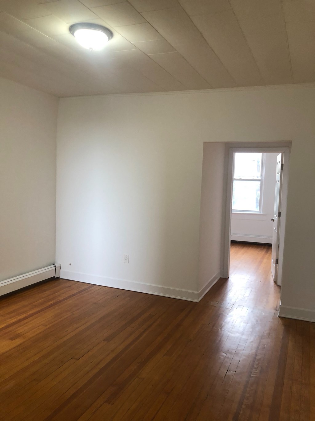 an empty living room with white walls and wooden floors