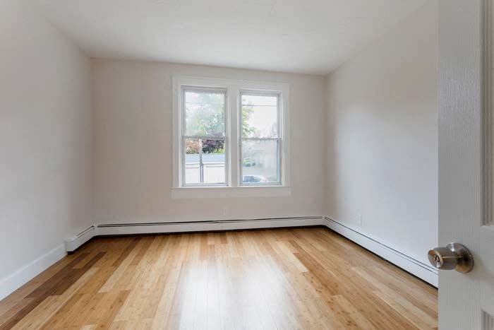 an empty room with a window and wooden floors