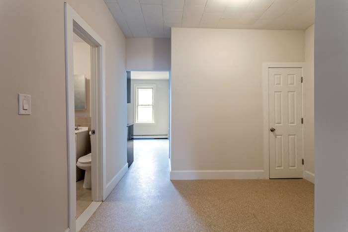 an empty hallway with a bathroom and a white door
